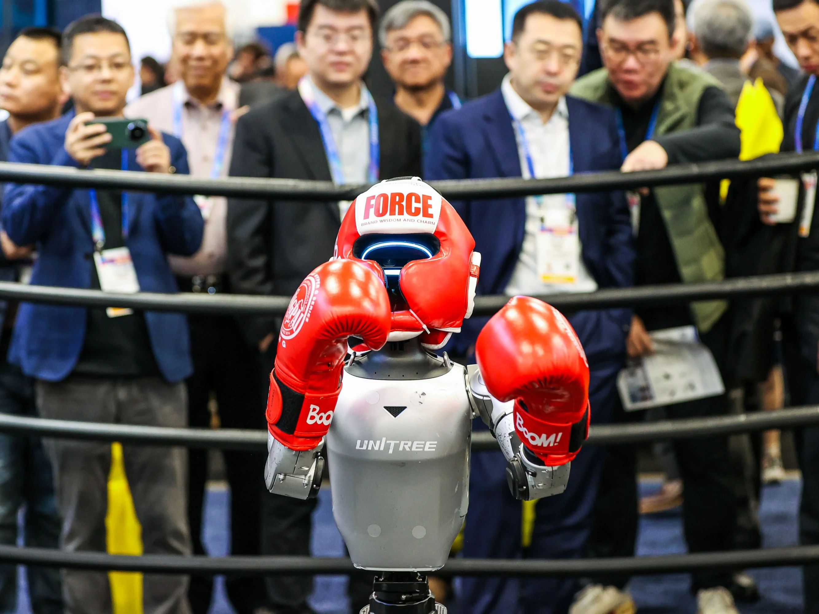 Attendees take photos of the UniTree autonomous robot which is posing with its boxing gloves and headgear